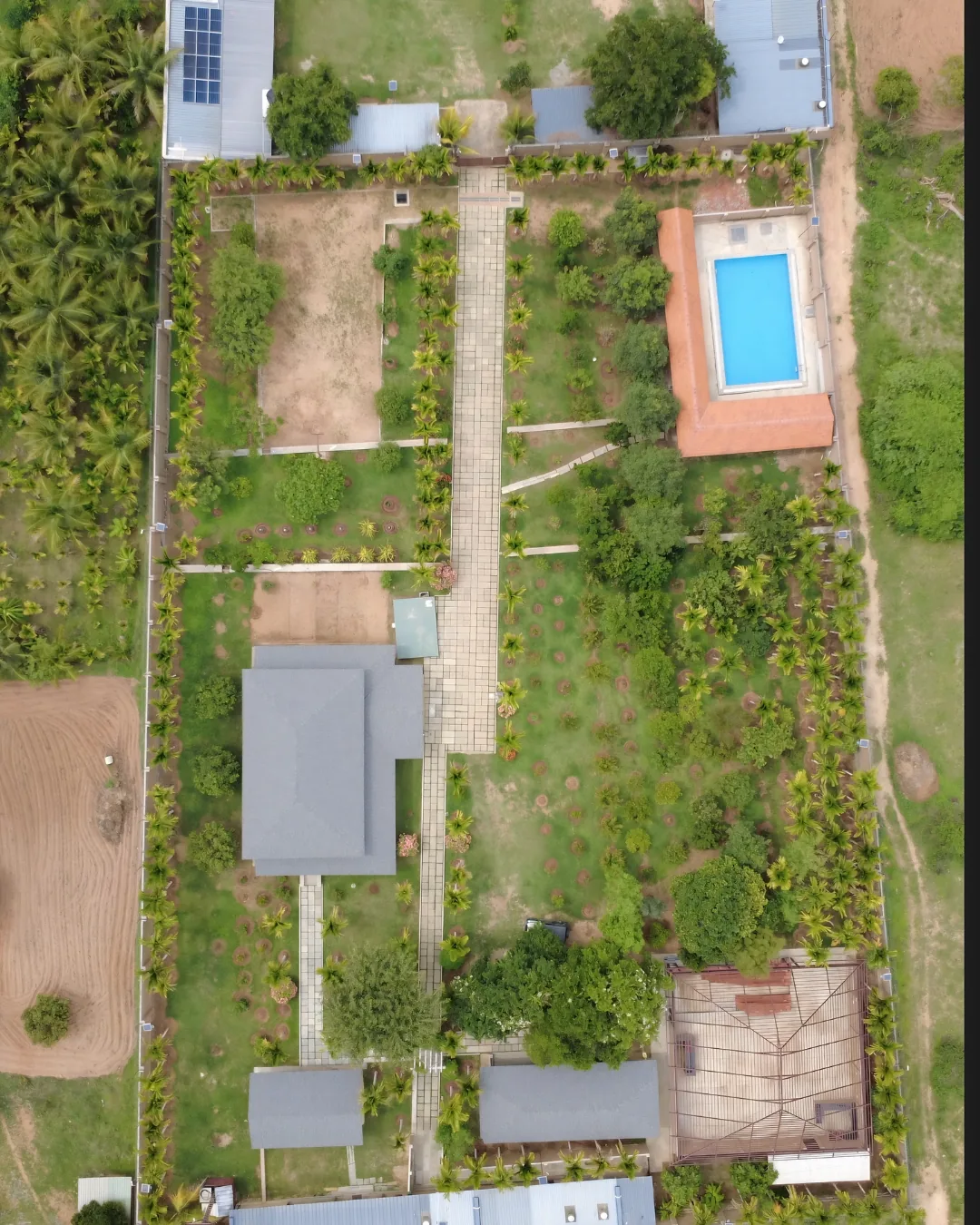The resort from above: guest blocks, orchard and pool inside a walled campus