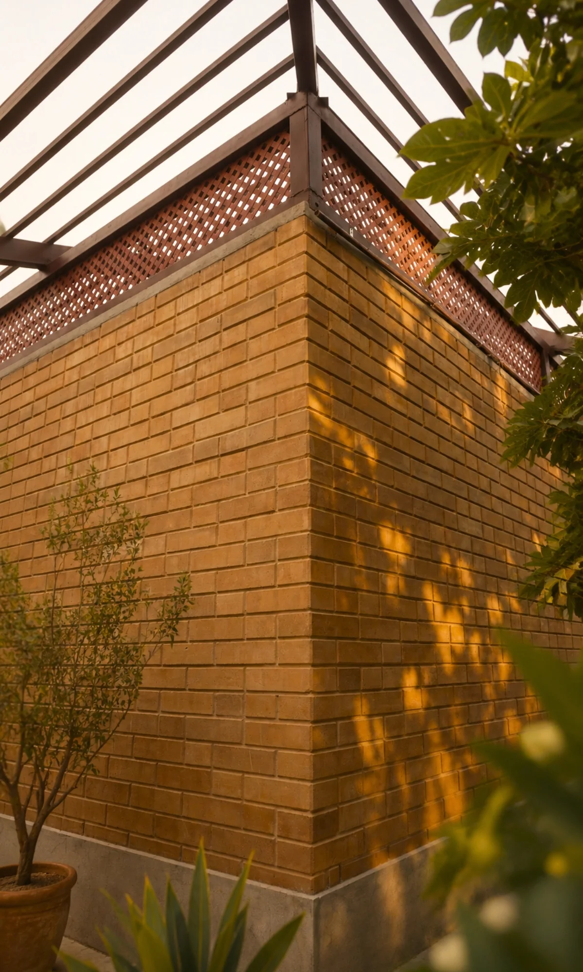 The corner of an exposed earth block wall at golden hour, low sun raking across every block face