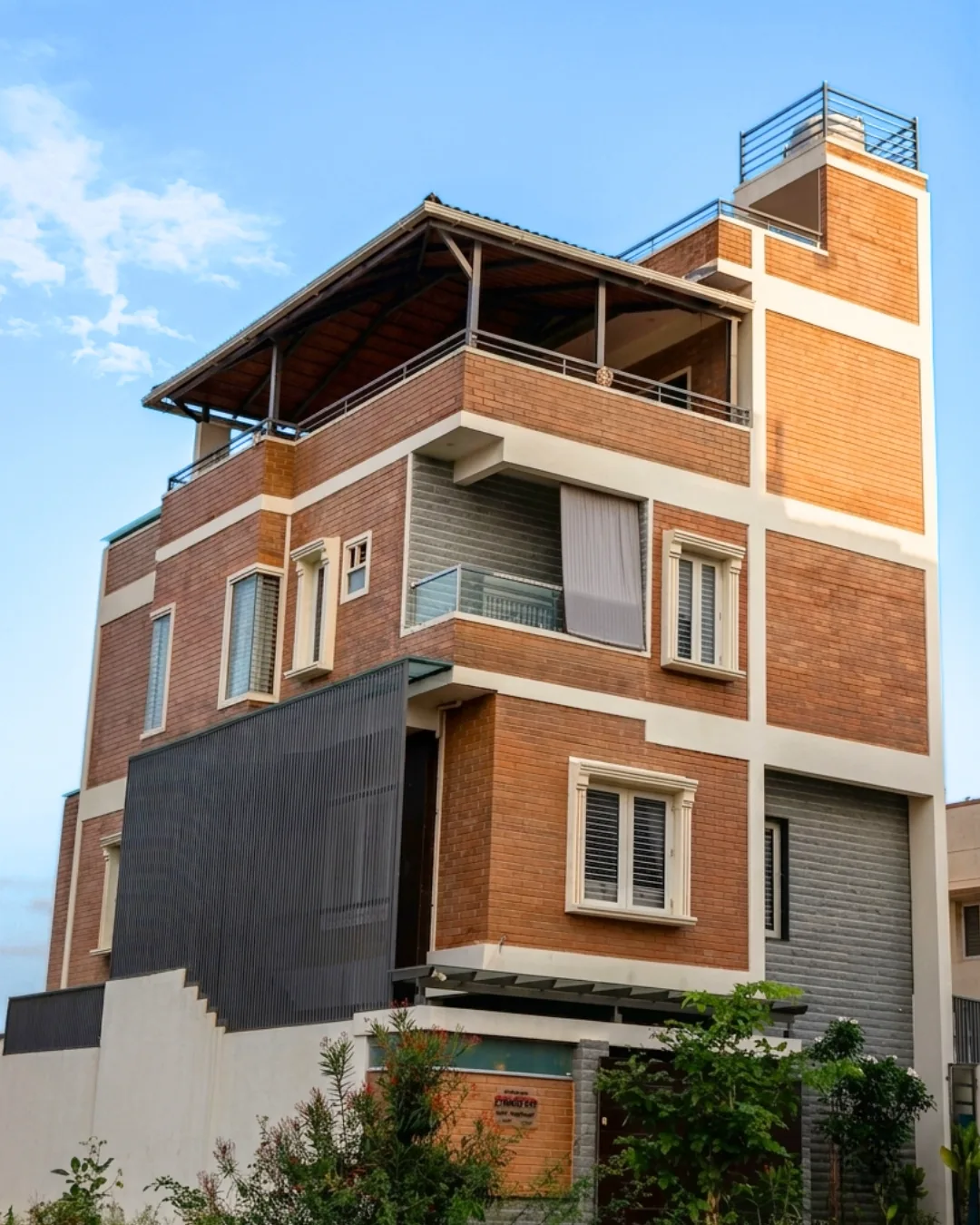The villa from the street, its earth-block faces banded with white render