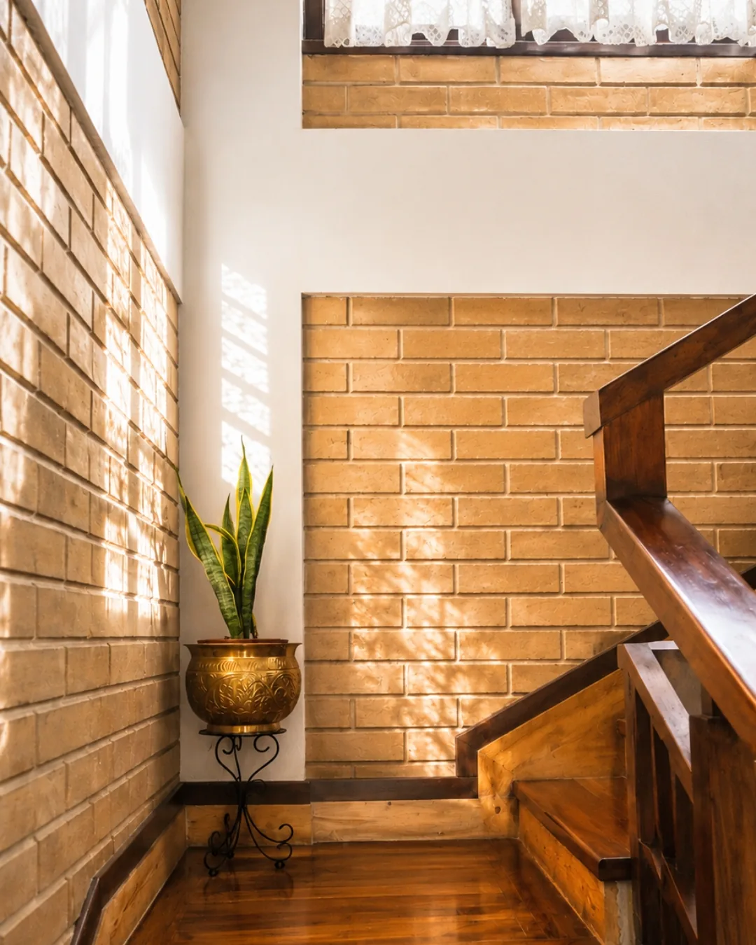 The stairwell, afternoon light raking across earth-block walls and a timber stair